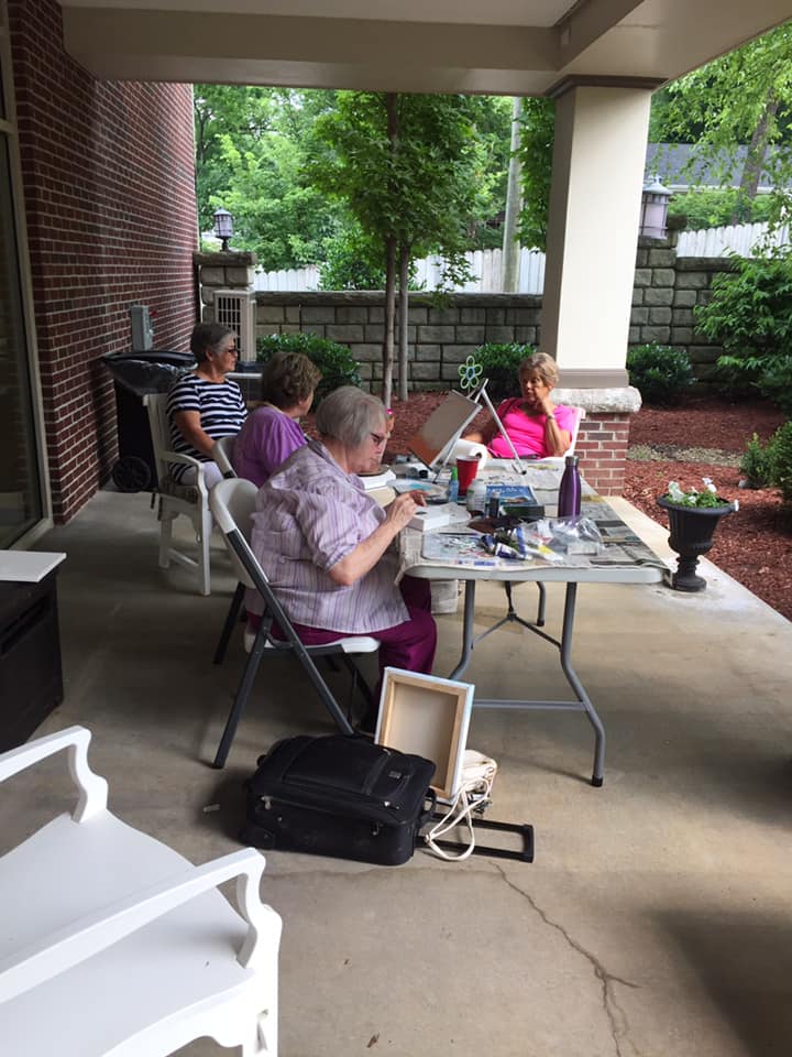 Sterling Meadows residents painting outdoors under the brick portico